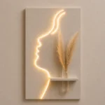 That's a beautiful piece — a glowing face silhouette LED wall art with a mini shelf and pampas grass. Very on-trend for home decor!